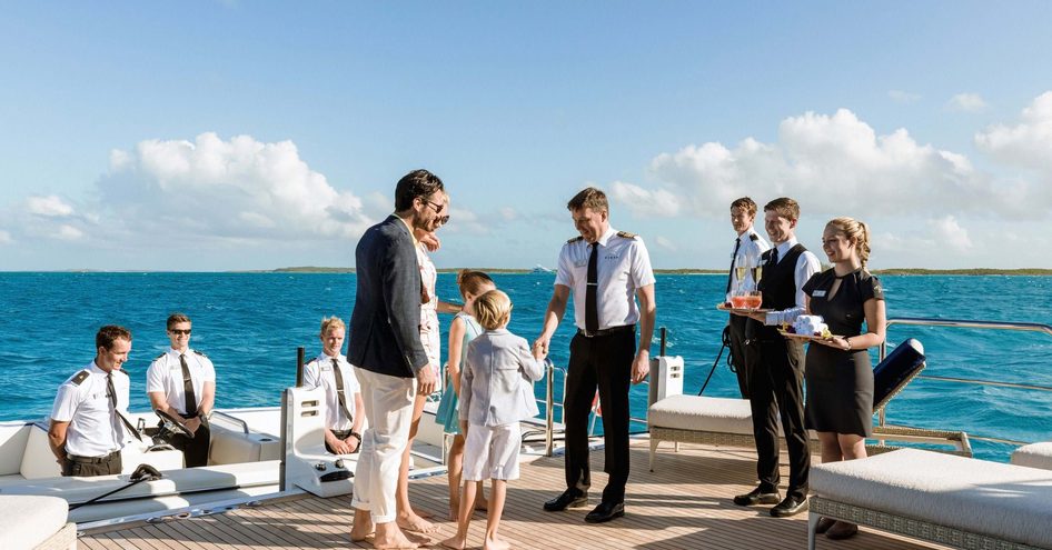 Professional yacht crew greeting yacht owner and guests onboard