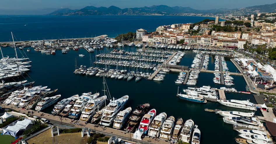 Aerial view overlooking Cannes Yachting Festival. Many motor yachts berthed in Vieux Port with exhibitor tents just visible to starboard.