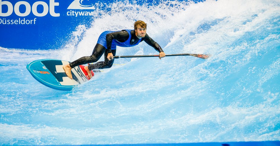 Watersports demonstration at Boot Dusseldorf, one surfer leaning into wave.