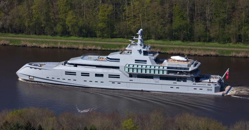 M/Y NORN underway along a river with green foliage in background.