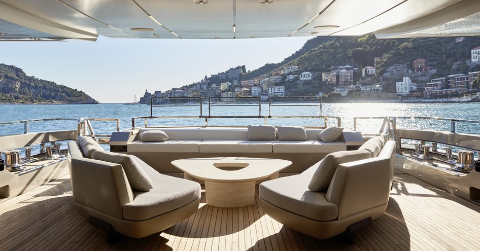 Exterior seating area on board Sanlorenzo 44 Alloy. Curved seats surround coffee table, overlooking Italian bay.