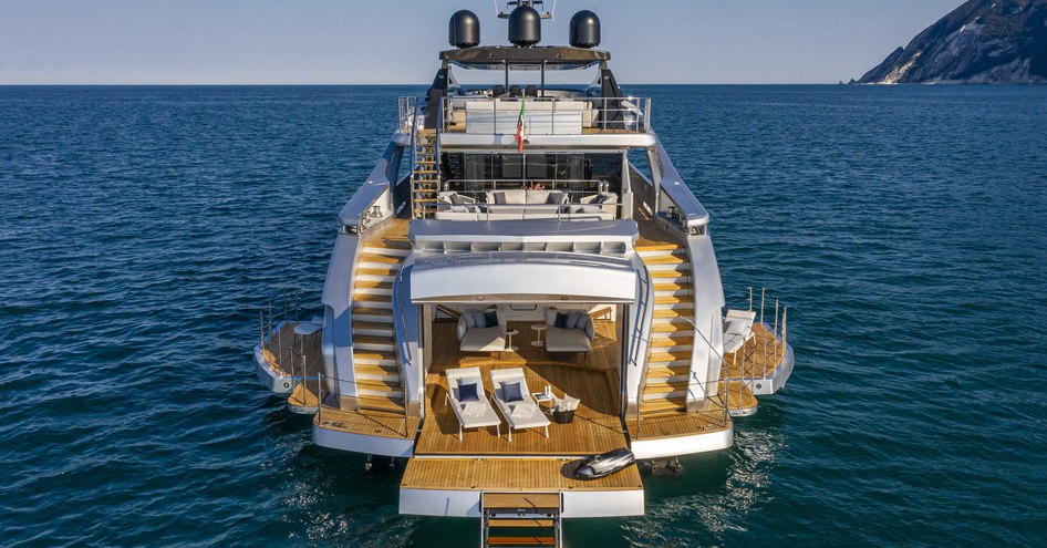 Beach Club onboard Pershing 140 'Touch Me', aft view of motor yacht, fold down balconies are on either side with sun loungers on the swim platform, surrounded by sea