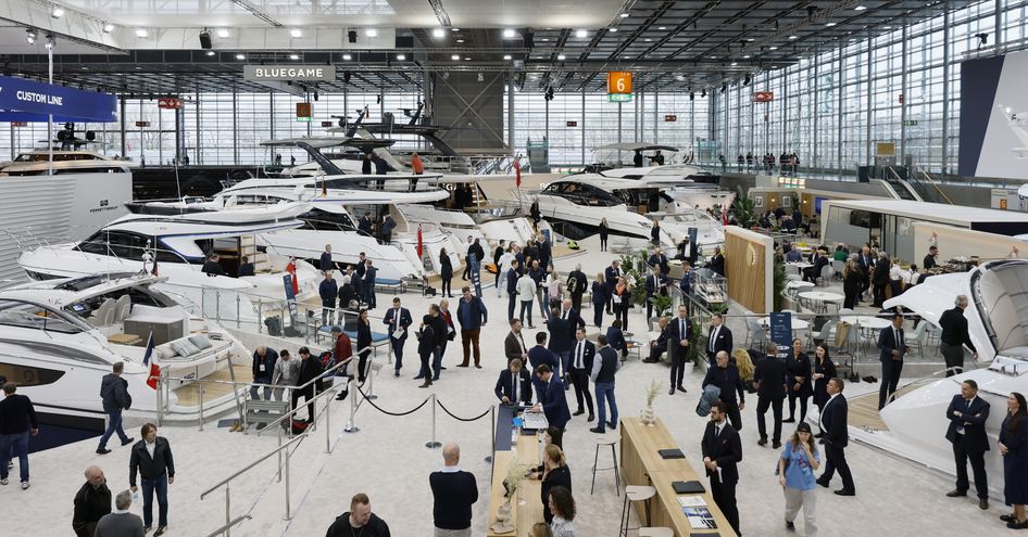 Overview of an exhibit hall during boot Dusseldorf, with many motor yachts for sale on display and visitors walking around 