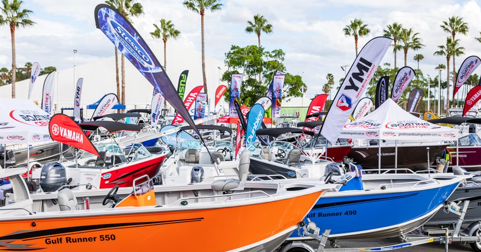 Tenders on display at Sanctuary Cove Boat Show, dry land exhibit with flags and tents in background.