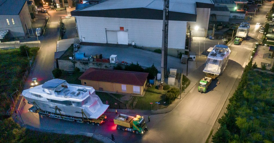 Elevated view of three Numarine 26XP units on trailers, moving along a road surrounded by shipyard buildings