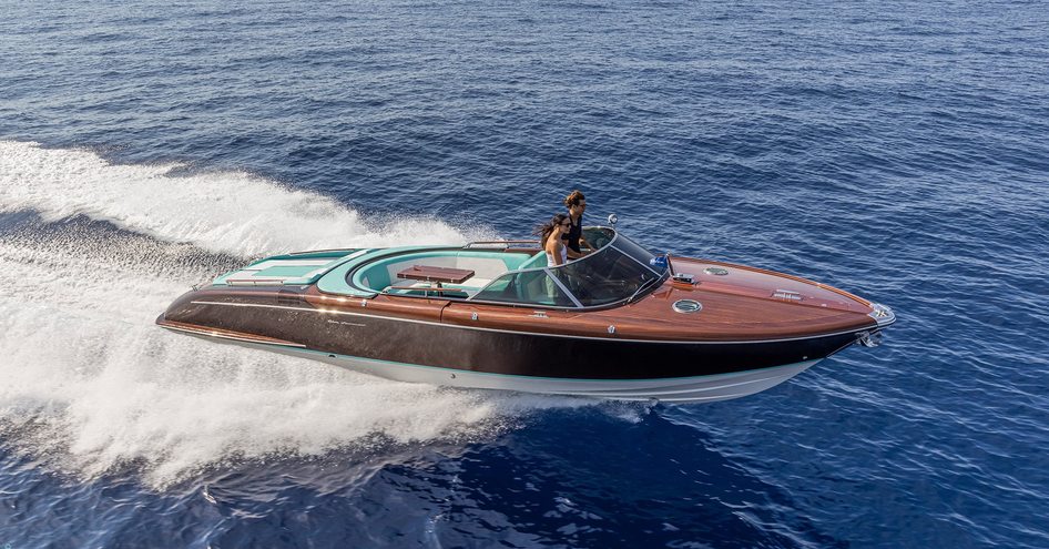 Riva Anniversario underway with two passengers onboard, surrounded by sea.