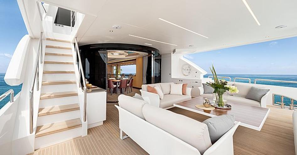 Rear view of Horizon Yachts FD102 cockpit, featuring three sofas around a coffee table, surrounded by blue skies and sea