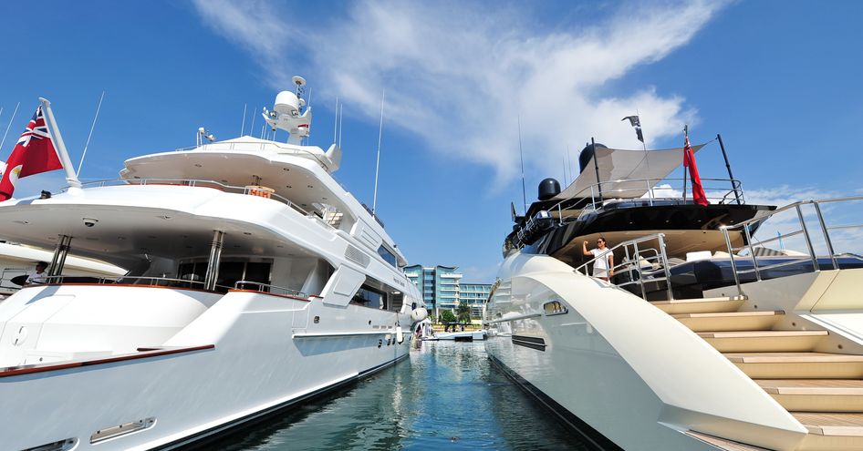 Aft view of two superyachts at anchor in marina