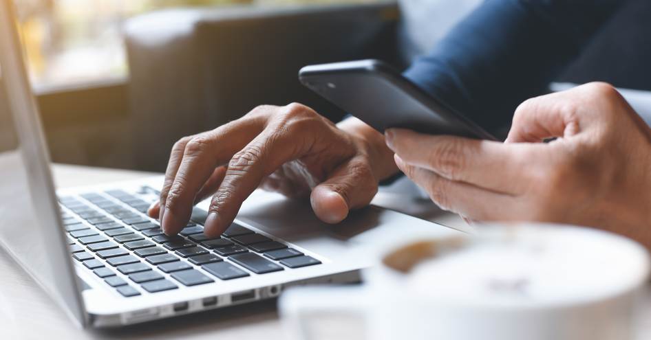 man looking on phone and laptop