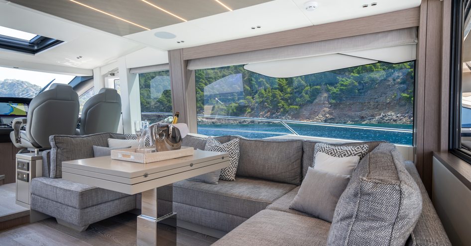 Overview of the main deck lounge area onboard the Sunseeker 75 Sport Yacht, U shaped seating in front of a large window.