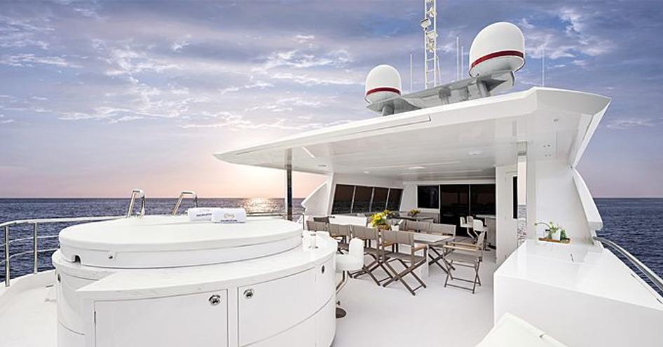 Rear angle view of Horizon Yachts FD102 deck with Jacuzzi and al fresco dining table and chairs