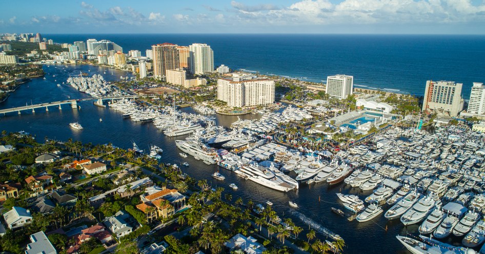 Elevated view of FLIBS, hundreds of yachts moored along pontoons, surrounded by green foliage and the sea over the horizon