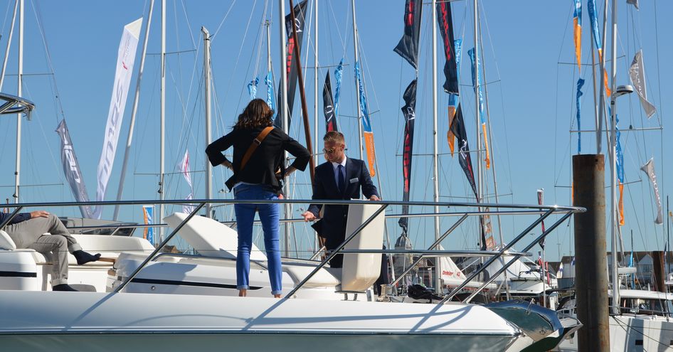 Brand representative giving talk to visitor onboard motor yacht at Southampton Boat Show