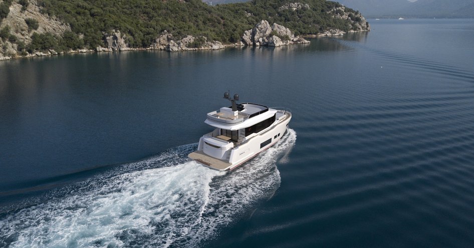 Aft view of Sirena 48 underway, surrounded by sea, heading towards some cliffs.