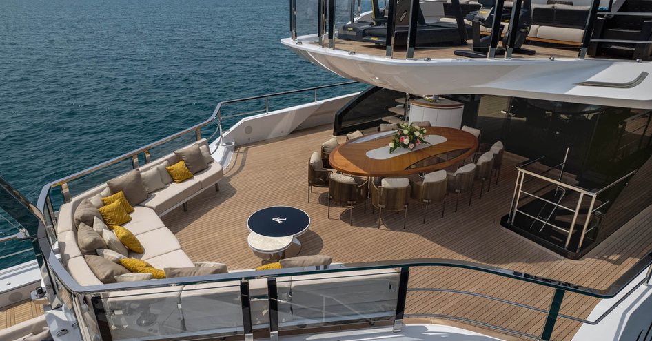 Overview of Mangusta Oceano 50 aft deck. Exterior lounge area with alfresco dining option on main deck, with extra seating just visible on upper deck.