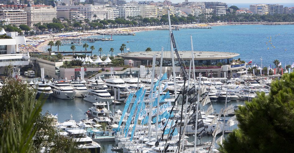 Overview image of Cannes Yachting Festival, collection of motor yachts in foreground with Cannes and sea in background