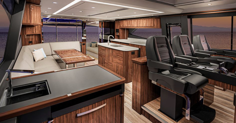 Overview of interiors inside Riviera 645 SUV, three helm seats in foreground with galley to starboard of image and seating on port side.