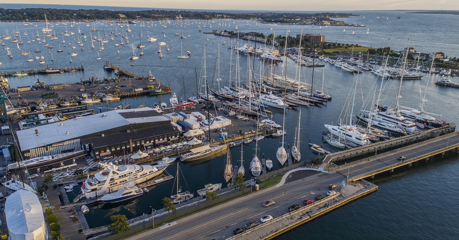 Elevated view of Safe Harbor Newport Shipyard, with multiple yachts moored, surrounded by sea