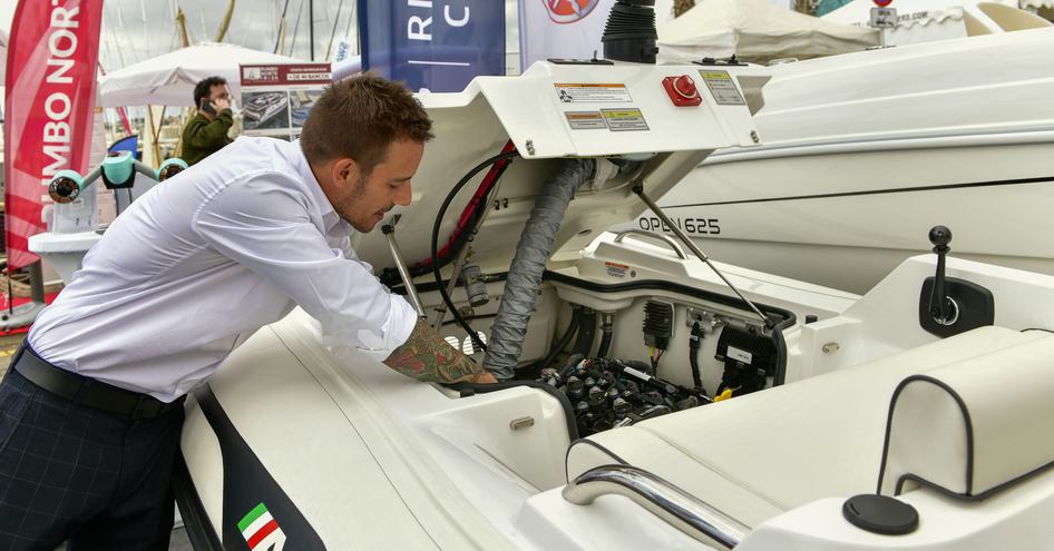 An exhibitor at the Palma International Boat Show inspecting an engine inside a displaying tender for sale