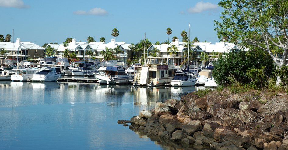 Overview of Sanctuary Cove marina, yachts berthed along dockside with white tents in background.