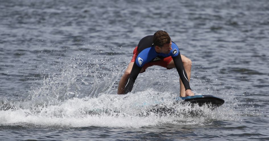 Man performing water sport demonstration on a paddle board, surrounded by sea