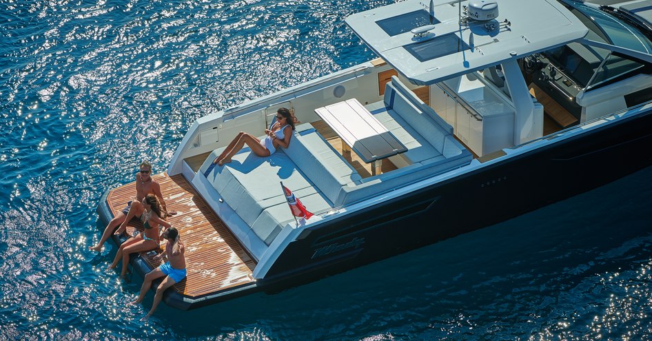 Guest relaxing on swimming platform of chase boat in sun