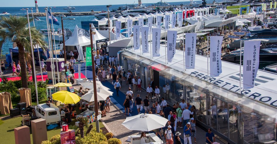 Overview of the Ferretti exhibitor stand at the Cannes Yachting Festival, with many visitors walking along out the front.