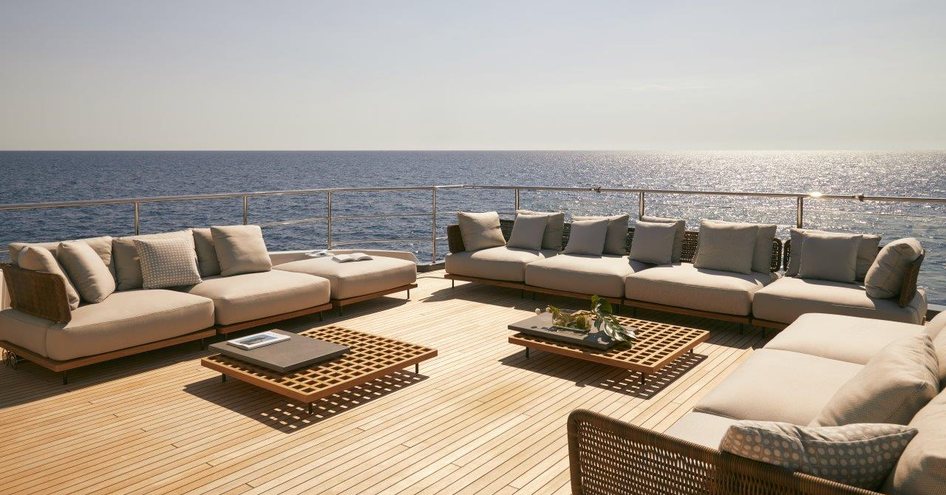 Sofas on deck of Benetti Diamond 145 INK superyacht, with two tables and sunny sky