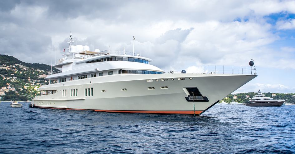 Superyacht Coral Ocean underway, surrounded by sea with land in distance port side.