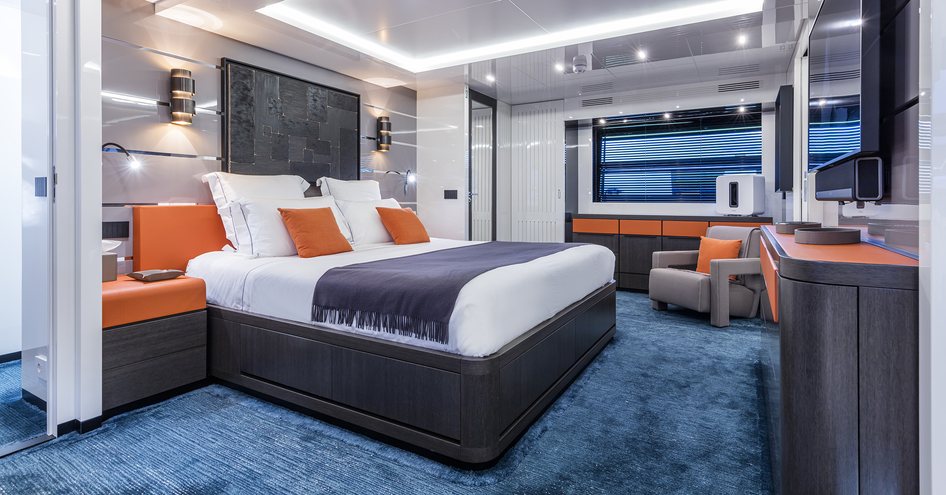 Double bed in master cabin of Sea Coral II with blue carpet and orange furnishings