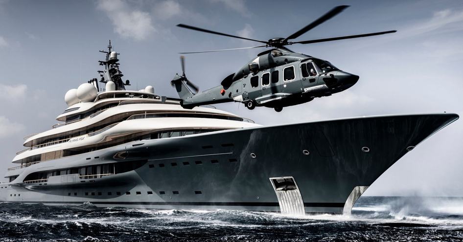 A helicopter landing on the bow helipad of Lurssen superyacht FLYING FOX