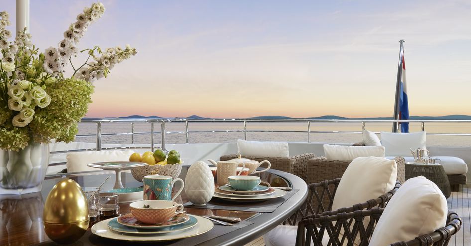 Laid out table with crockery and seats on deck of superyacht ARKADIA