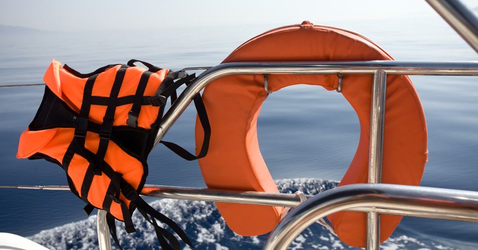 Lifejacket over railing of yacht next to lifebuoy