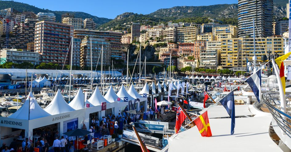 View across boat show with crowds of people, flags and exhibition marquees