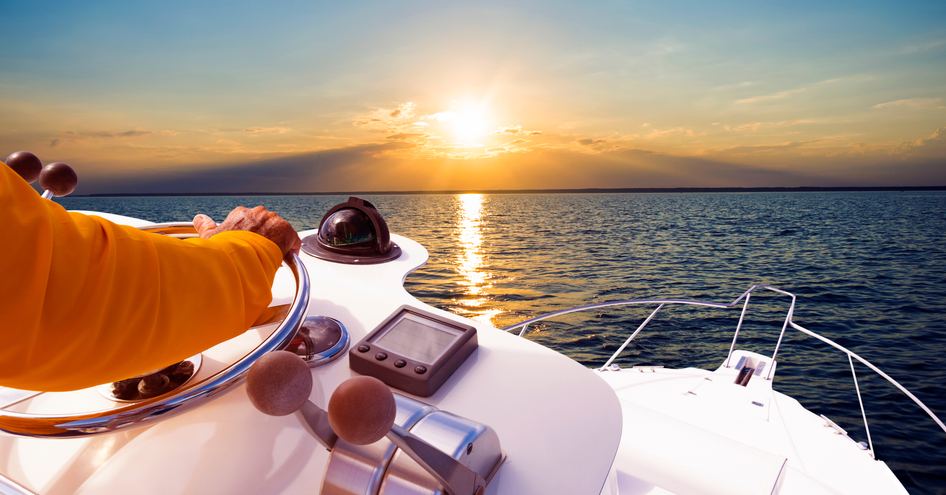 Hand of captain on steering wheel of motor boat in the blue ocean 