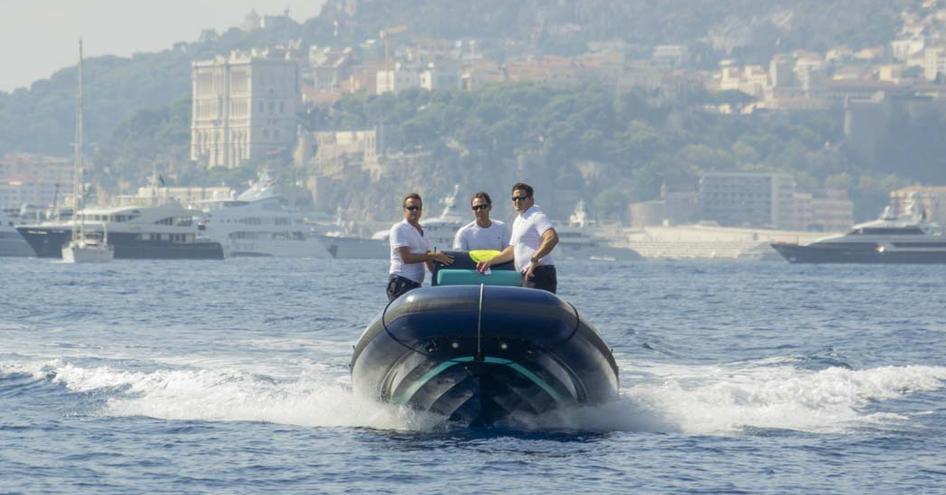 Three males on SOLAS tender with rugged coast in background