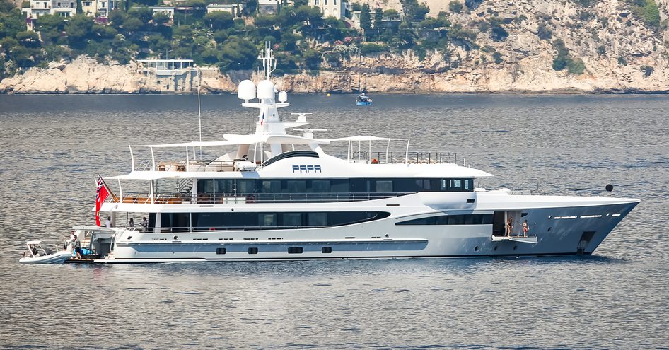 Sideview of M/Y PAPA underway at sea, with elevated terrain in the background.