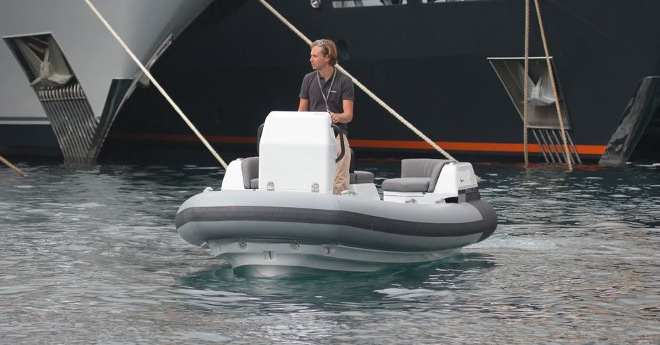 Man on small RIB in front of yachts