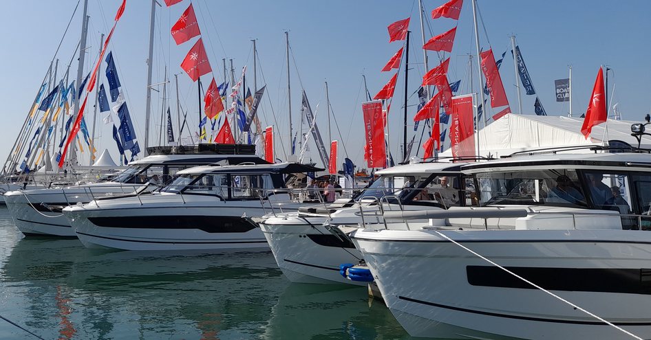 Motor yachts for sale berthed at the Southampton International Boat Show with flags in the background