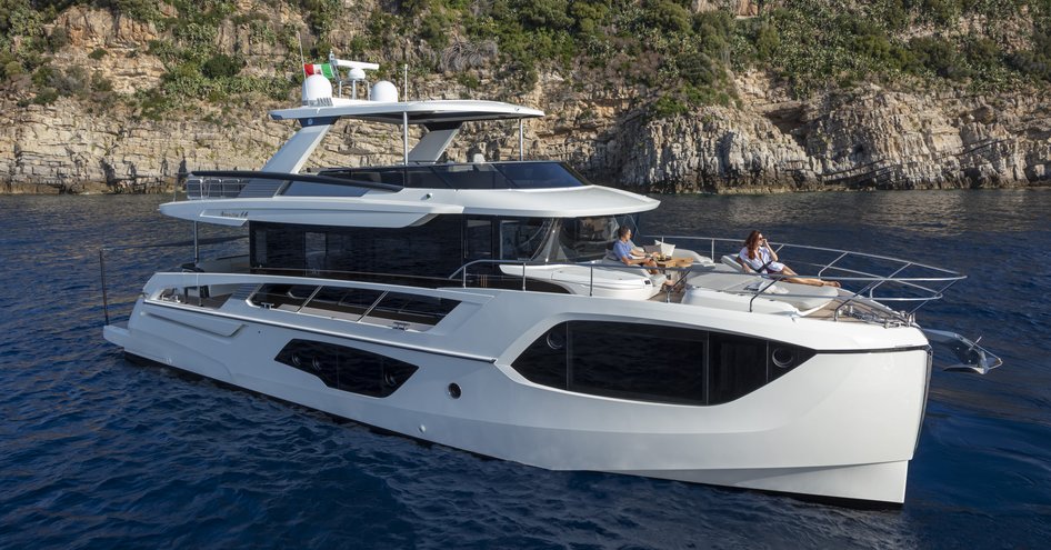 Absolute Navetta 64 at anchor, surrounded by sea and high cliffs in background.